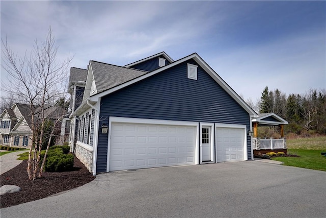view of side of property with a shingled roof and driveway