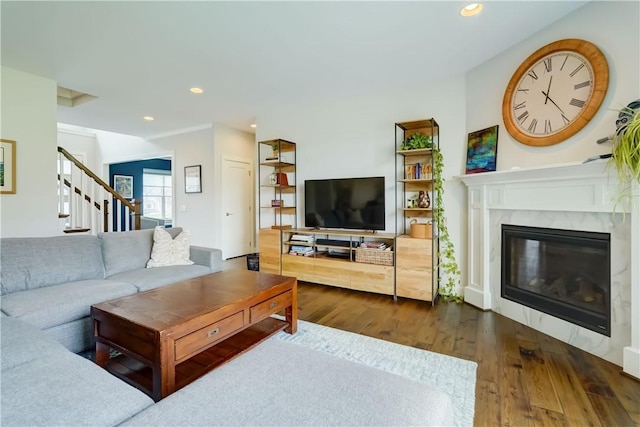 living room featuring recessed lighting, a high end fireplace, stairs, and dark wood-style flooring