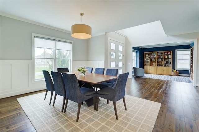 dining room with wainscoting, a decorative wall, and hardwood / wood-style flooring