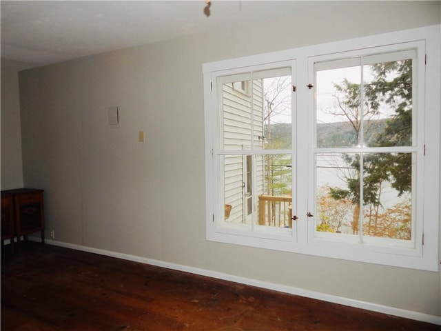 unfurnished room featuring baseboards and dark wood-type flooring
