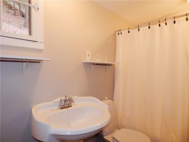 bathroom with a sink, a shower with shower curtain, and toilet