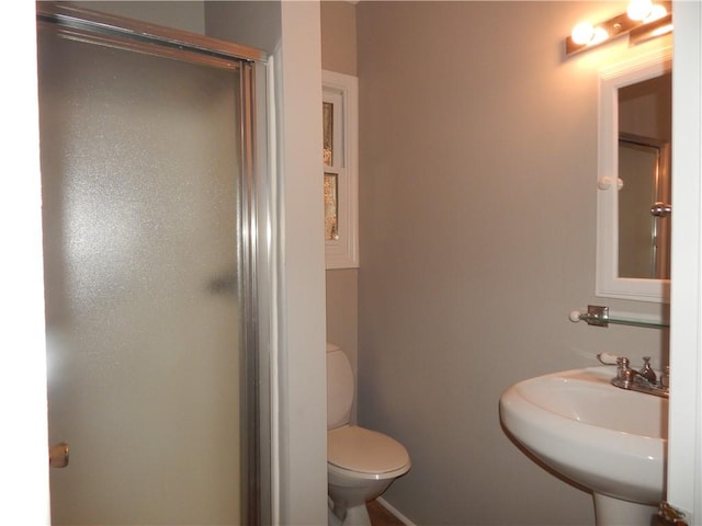 bathroom with toilet, a shower stall, and a sink
