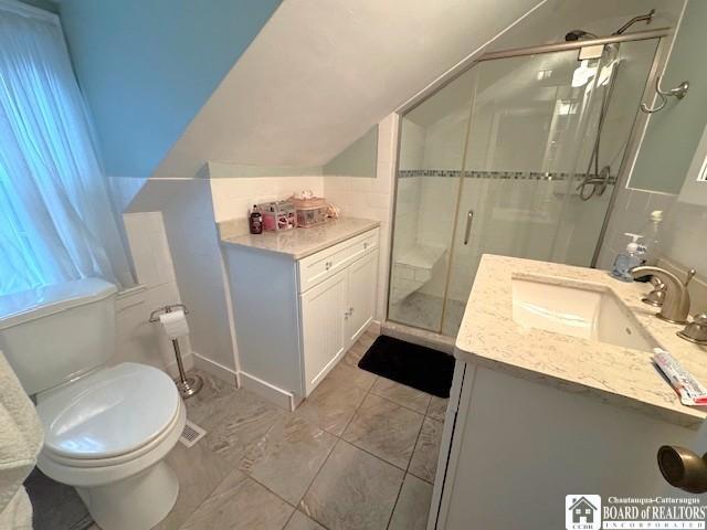 bathroom featuring tile patterned flooring, a stall shower, vanity, toilet, and lofted ceiling