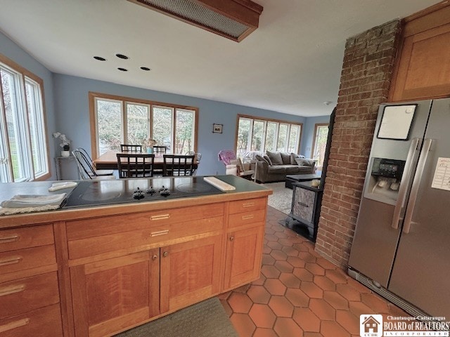 kitchen featuring stainless steel refrigerator with ice dispenser, a wood stove, black electric stovetop, recessed lighting, and light tile patterned flooring