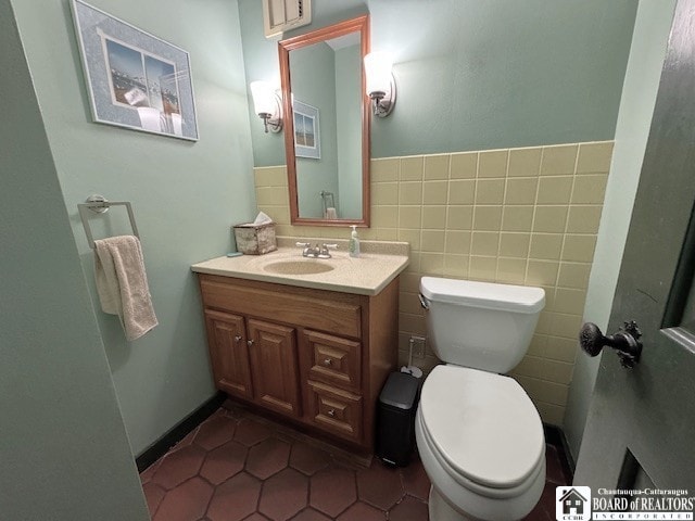half bath featuring vanity, tile patterned flooring, and toilet