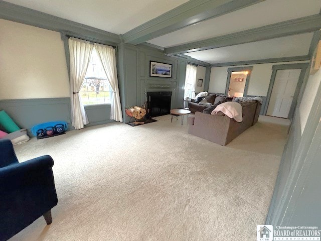 carpeted living room featuring a fireplace, a wainscoted wall, and beamed ceiling