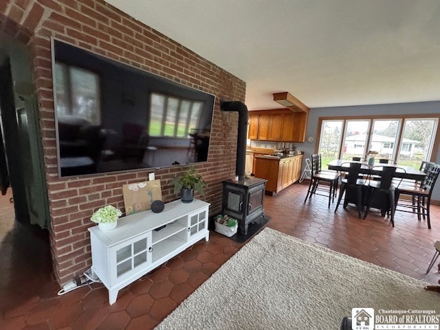 living room with dark tile patterned floors, a wood stove, and brick wall