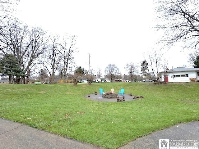 view of community featuring a fire pit and a yard