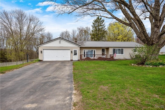 single story home with metal roof, a front yard, a wooden deck, aphalt driveway, and an attached garage