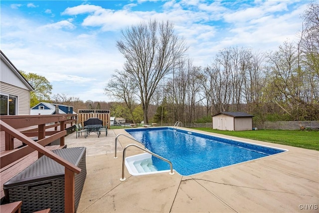 view of swimming pool featuring a patio, a storage unit, a fenced in pool, a lawn, and an outbuilding