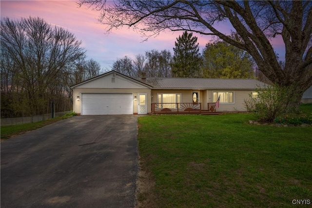 single story home featuring a garage, aphalt driveway, a wooden deck, metal roof, and a lawn