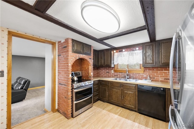 kitchen featuring dark brown cabinetry, appliances with stainless steel finishes, a sink, light countertops, and light wood finished floors