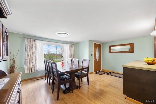dining room featuring baseboards, light wood-type flooring, and visible vents