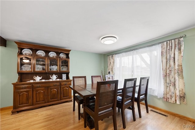 dining area with visible vents, light wood-style floors, and baseboards