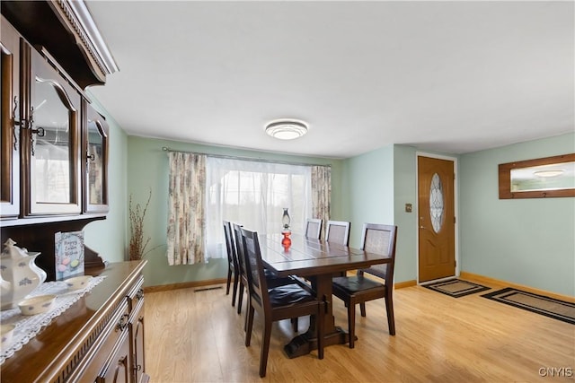 dining area featuring baseboards, light wood finished floors, and visible vents