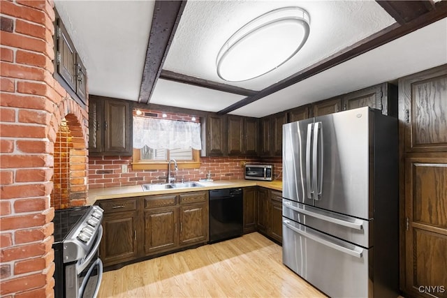 kitchen featuring a sink, appliances with stainless steel finishes, light wood-style flooring, and light countertops