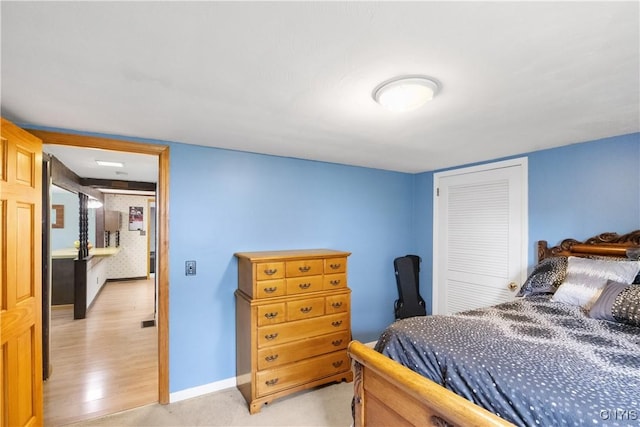 bedroom featuring baseboards, light wood-style flooring, and a closet