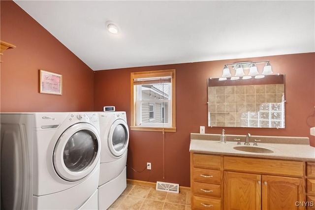 washroom with visible vents, light tile patterned flooring, baseboards, separate washer and dryer, and a sink