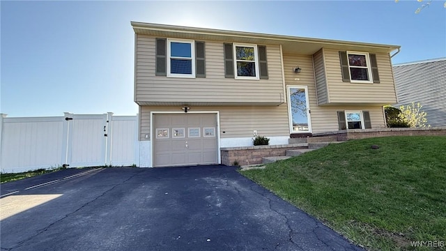 split foyer home featuring fence, an attached garage, driveway, and a front yard