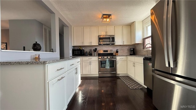 kitchen featuring appliances with stainless steel finishes, decorative backsplash, light stone countertops, and dark wood-style flooring