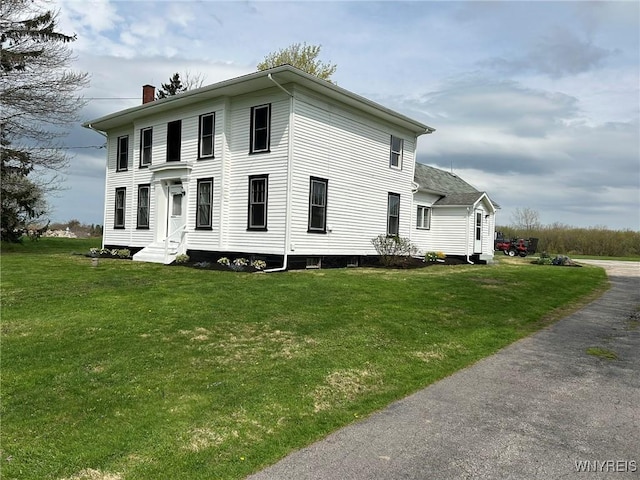 view of home's exterior featuring a yard, a chimney, and entry steps