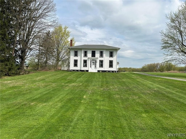 view of front facade with a chimney and a front yard