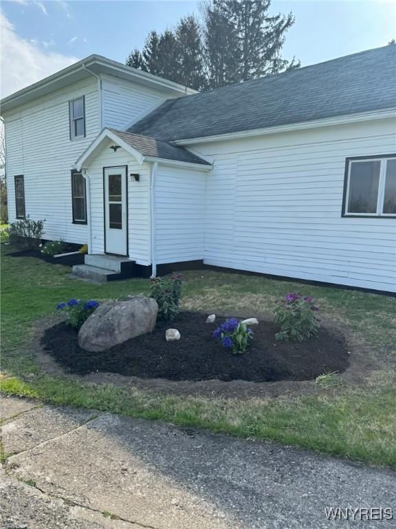 view of front of property with roof with shingles and a front lawn