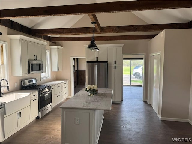 kitchen featuring a kitchen island, stainless steel appliances, hanging light fixtures, and white cabinetry