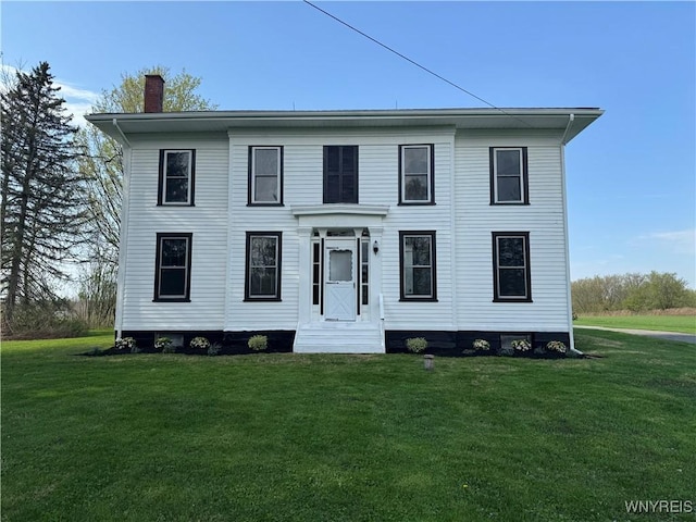 colonial-style house featuring a chimney and a front yard