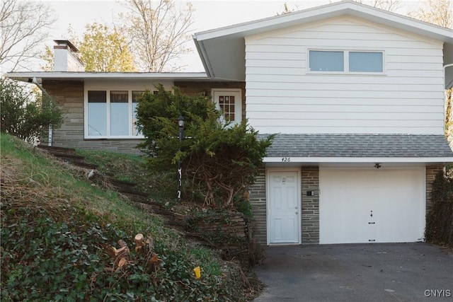 view of front of home with a garage, a chimney, and driveway