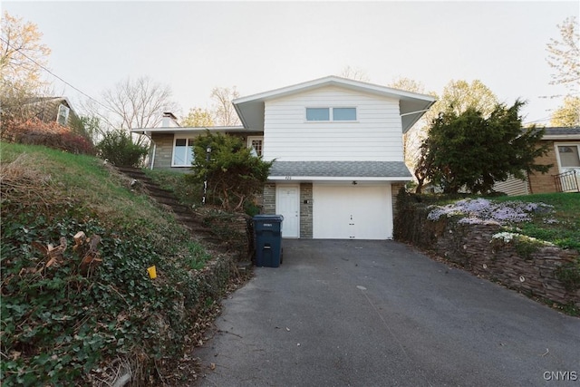 view of side of property with an attached garage, aphalt driveway, a chimney, and stone siding