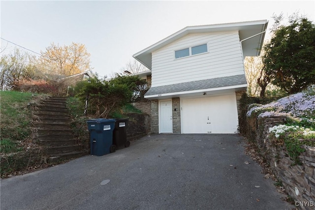 view of property exterior featuring a garage, driveway, roof with shingles, and stone siding