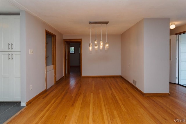 unfurnished dining area with baseboards, light wood-style flooring, and visible vents