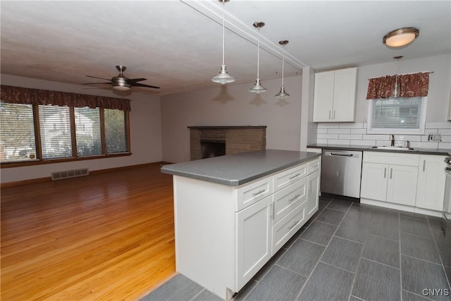 kitchen with dark countertops, ceiling fan, a sink, dishwasher, and visible vents