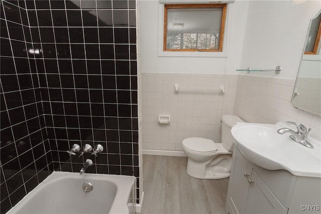 full bathroom with vanity, wood finished floors, toilet, tile walls, and shower / washtub combination