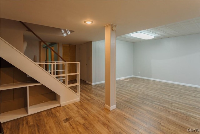 finished below grade area with baseboards, stairs, and wood finished floors