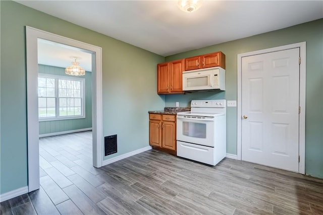 kitchen with visible vents, brown cabinetry, wood finished floors, white appliances, and baseboards