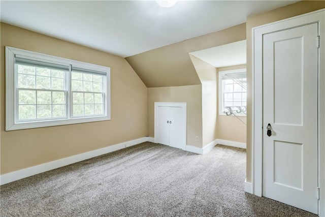 additional living space with baseboards, carpet flooring, and vaulted ceiling