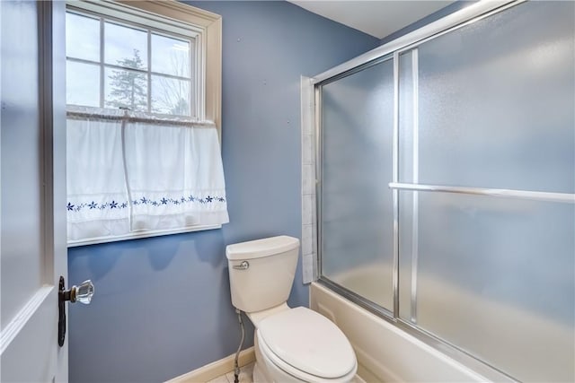 full bath featuring baseboards, bath / shower combo with glass door, and toilet