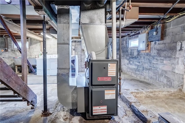 utility room featuring heating unit, separate washer and dryer, and electric panel
