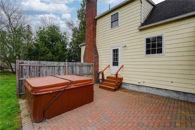 view of patio / terrace featuring a hot tub, fence, and entry steps