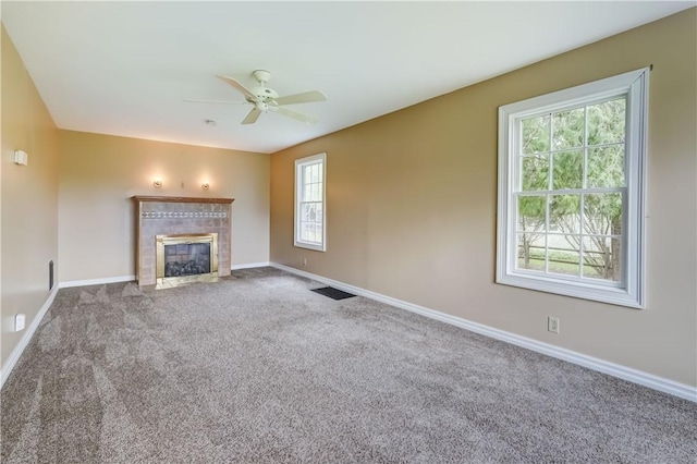 unfurnished living room featuring a tiled fireplace, baseboards, carpet, and a ceiling fan