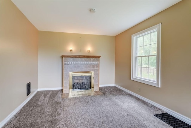 unfurnished living room with visible vents, carpet floors, and a tile fireplace