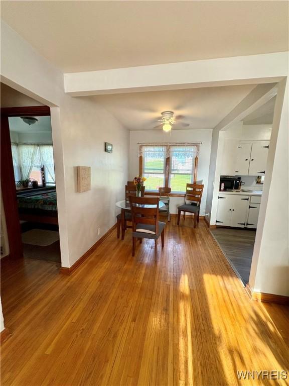 dining space featuring baseboards, a ceiling fan, wood finished floors, and beamed ceiling
