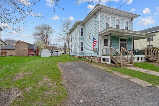 italianate-style house featuring an outbuilding, a front lawn, a storage shed, and covered porch