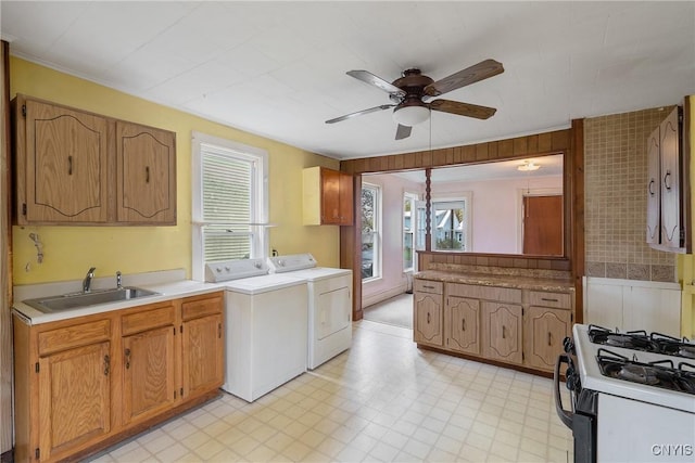 washroom featuring laundry area, a ceiling fan, washing machine and clothes dryer, a sink, and a wealth of natural light