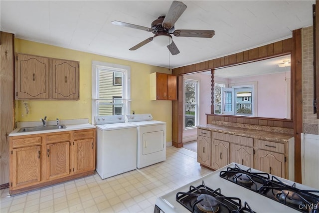clothes washing area featuring laundry area, a ceiling fan, independent washer and dryer, a sink, and light floors