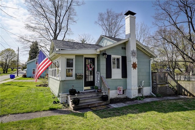 bungalow with fence, a front yard, roof with shingles, a chimney, and entry steps