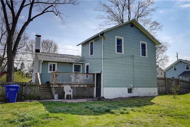 back of property with a chimney, a fenced backyard, a lawn, and a deck