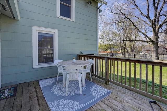 wooden deck with a lawn, fence, and outdoor dining space